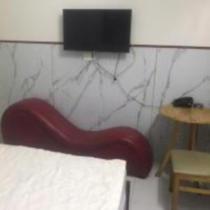 a red chair in a room with a tv on the wall at Du Thuyền 2 Hotel Hồ Chí Minh in Ho Chi Minh City