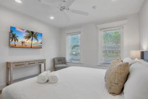 a white bedroom with a bed with two towels on it at Barefoot by the Bay at Bayside Bungalow in Anna Maria +18 photos