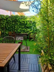 Un patio con una mesa de madera y un seto verde. en apto 2 hab y jardín cerca de Alcalá de Henares, en Villalbilla
