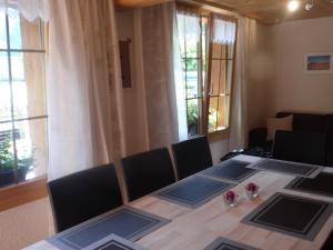 ein Esszimmer mit einem Tisch, Stühlen und Fenstern in der Unterkunft Appartment Chalet Sonnenheim in Kandersteg