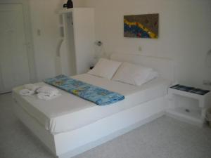 a white bed in a white room with towels on it at Ostria Vento in Pollonia