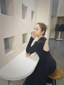 a woman in a black dress sitting at a table at Xi You Hotel禧又 - near Xi'an City Wall, Daming Palace, with ticket service for featured scenic spots ,Paid Airport shuttle and tour charter services available,Welcome gifts and a cup of freshly ground coffee in Xi'an