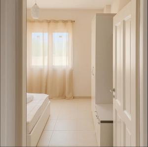 a white room with a bed and a window at Beach Apartment Relax & Unwind in Lalzit Bay