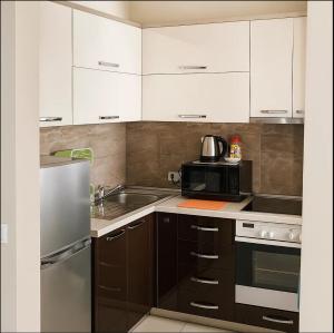 a kitchen with white cabinets and a sink and a microwave at Beach Apartment Relax & Unwind in Lalzit Bay