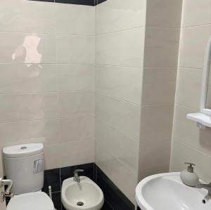 a white bathroom with a toilet and a sink at Beach Apartment Relax & Unwind in Lalzit Bay +1 photo