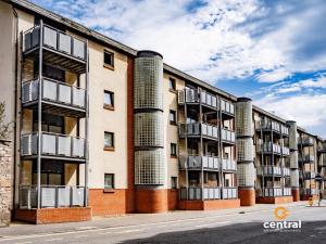 an apartment building with four chimneys on a street at Trades Lane by CENTRAL SERVICED APARTMENTS - City Centre - 2 Bedrooms - En-Suite Bathroom - Dedicated Parking Space - Fully Equipped - Walk Away From Dundee Bus & Train Station - City Centre - Fully Equipped in Dundee