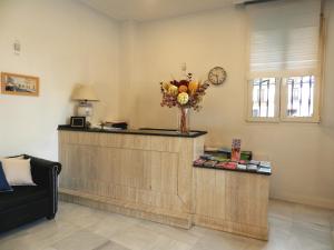 a lobby with a reception counter with a vase of flowers at Hotel Doña Blanca in Seville