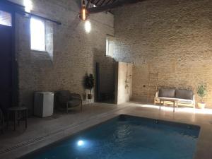 a swimming pool in a room with a brick wall at Maisonnette de charme - Piscine intérieure privée chauffée en option in Luc-sur-Mer