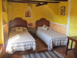 2 Betten in einem Zimmer mit gelben Wänden in der Unterkunft El Ensueño in Caneto
