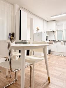 a white table and chairs in a white kitchen at Luna stay in Seoul