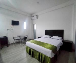 ein Hotelzimmer mit einem großen Bett und einem Tisch in der Unterkunft Wisma Samrat in Rantepao