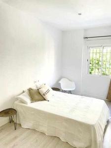 a white bedroom with a large bed and a window at Elegante apartamento 6-8pax AV Palmera 3D 2B in Seville