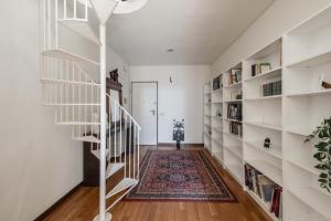 a hallway with white bookshelves and a spiral staircase at Single House in Pisa