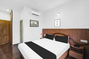 a bedroom with a large bed with a wooden headboard at Townhouse Oak Mysuru City Bus Terminal in Mysore