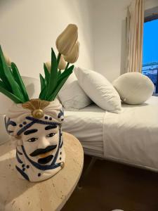 a vase on a table next to a bed at Cairoli House- Grottammare in Grottammare