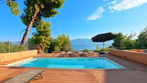 a swimming pool with chairs and an umbrella on a deck at Askalosia villa in Agios Georgios