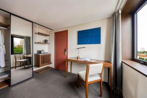 a hotel room with a desk and a window at Signature by M Village Thợ Nhuộm in Hanoi