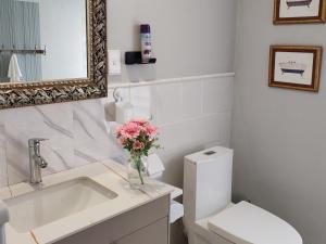a white bathroom with a toilet and a vase of flowers at Sandton Spring Rivonia in Johannesburg