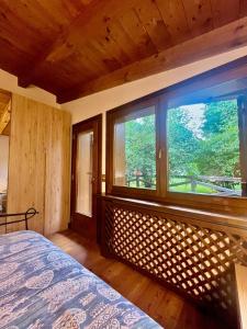a bedroom with a bed and a large window at Relax & Elegance apartment near Cortina in San Vito di Cadore