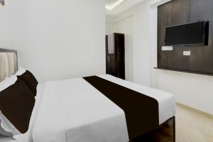 a bedroom with a bed and a tv on a wall at Collection O Mahadevapura Opposite Phoenix Mall in Bengaluru