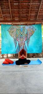 a woman sitting on the floor in front of a mural at Ginger Harmony Guesthouse and Cafe in Tangalle