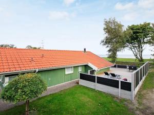 a green house with a deck with two dogs on it at Seaside Bliss with Spa - By Traum Ferienwohnungen in Otterup