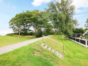 a grassy hill next to a road with a tree at Seaside Bliss with Spa - By Traum Ferienwohnungen in Otterup