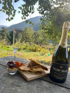 a bottle of wine and a plate of food and a glass at Guest House Tobuldar in Kʼveda Marghi
