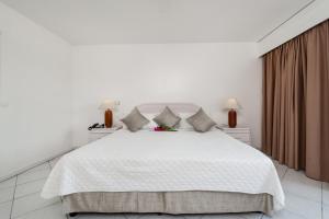 a white bedroom with a white bed and two lamps at Charming apartment in Lowlands with shared pool, 87 m² in Lowlands +7 photos