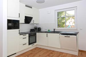 eine weiße Küche mit weißen Schränken und einem Fenster in der Unterkunft Haus Eichkater in Dierhagen