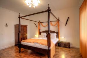 a bedroom with a four poster bed with orange sheets at Hotel Zum Goldenen Stern in Prüm