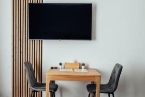 a table with two chairs and a television on a wall at The Bašty Stay in Brno