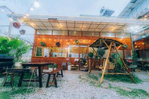 a restaurant with tables and a swing in front of it at D Home Retreat Hùng Vương Đà Lạt in Khu Chi Lăng