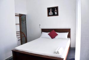 Un dormitorio con una cama blanca con almohadas rojas y blancas. en Sureka Home Stay, en Habaraduwa Central