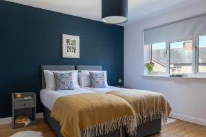 a bedroom with blue walls and a bed with pillows at Modern 3 bedroom house Llanrwst less than a 5 minute drive from Zip World Forest in Llanrwst