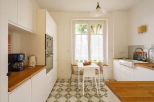 a white kitchen with a table and a small table at Ker Gaïdic - Proche Plage in Bénodet