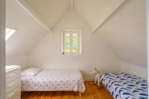 a attic bedroom with two beds and a window at Ker Gaïdic - Proche Plage in Bénodet