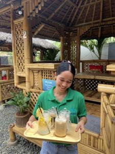 a woman holding a tray with drinks in mason jars at Mongki's Pensionhouse in Puerto Princesa City