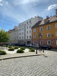 a cobblestone street in a city with buildings and cars at Apartament na Placu Swietego Sebastiana in Opole