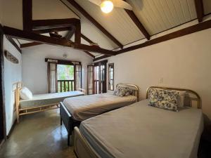 a room with two beds and a bench in it at Casa Yacht Club in Ilhabela
