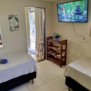 a room with two beds and a tv on the wall at L&M Housing Apartamentos y casa in Búzios