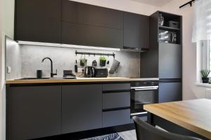 a kitchen with black cabinets and a wooden table at Apartmány Hřensko in Hřensko