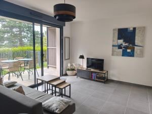 a living room with a couch and a tv at STELLA Modern apartment, terrace and sea view Donville in Donville-les-Bains