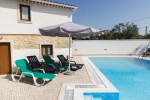 a pool with chairs and an umbrella next to a house at Casa Oliveira in Fátima
