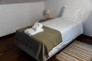 a bedroom with a bed with white sheets and a rug at Casa Oliveira in Fátima