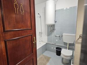 a bathroom with a toilet and a wooden door at Blife Portugalya - private rooms at Santantonya 2nd floor in Faro +8 photos
