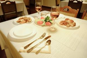 a white table with plates of food and glasses of wine at Enjoy Inn in Pilsen