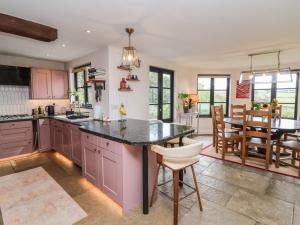 a kitchen with pink cabinets and a dining room at Hedgerose in Goodleigh