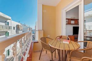 balcón con mesa de madera, sillas y ventana en Casa Amanecer Atlántico 2 Izquierda, en Playa de San Juan