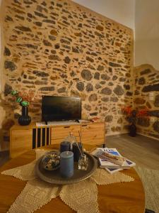 a living room with a table with a laptop on a stone wall at Porta Mesta in Chios